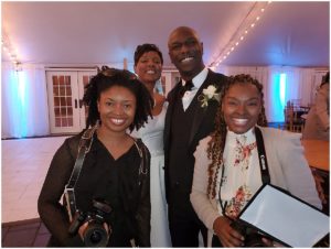 Two women carrying camera gear pose with a bride and groom in Richmond