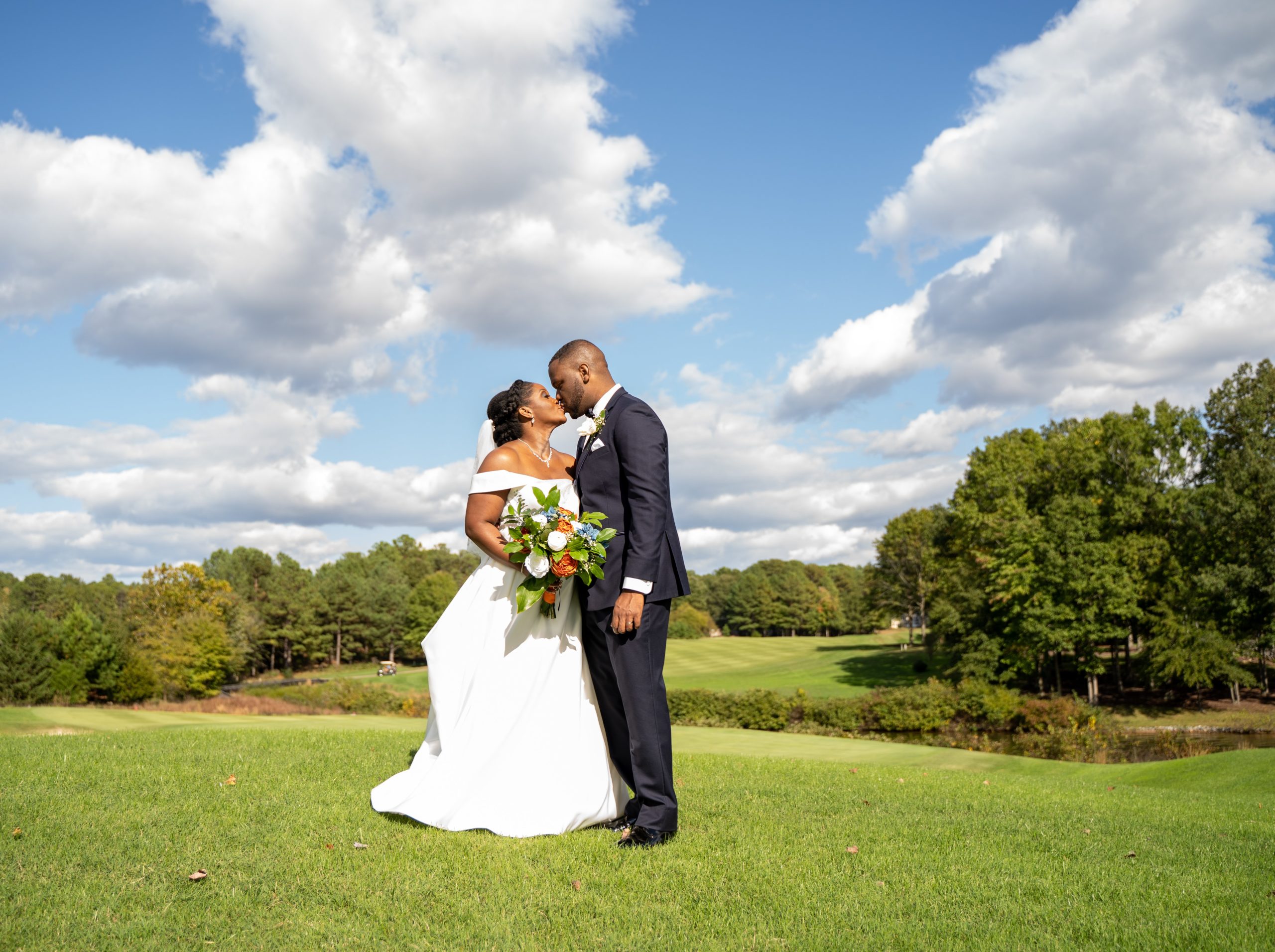 A bride and groom kiss on a golf course