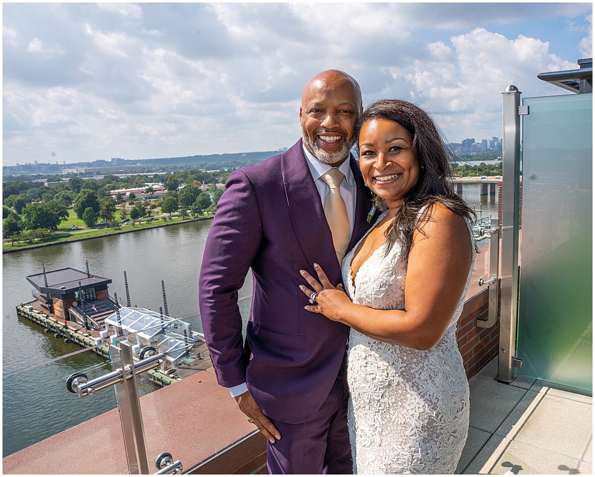 Couple dressed in wedding attire stand on the balcony of the Intercontinental DC Wharf.