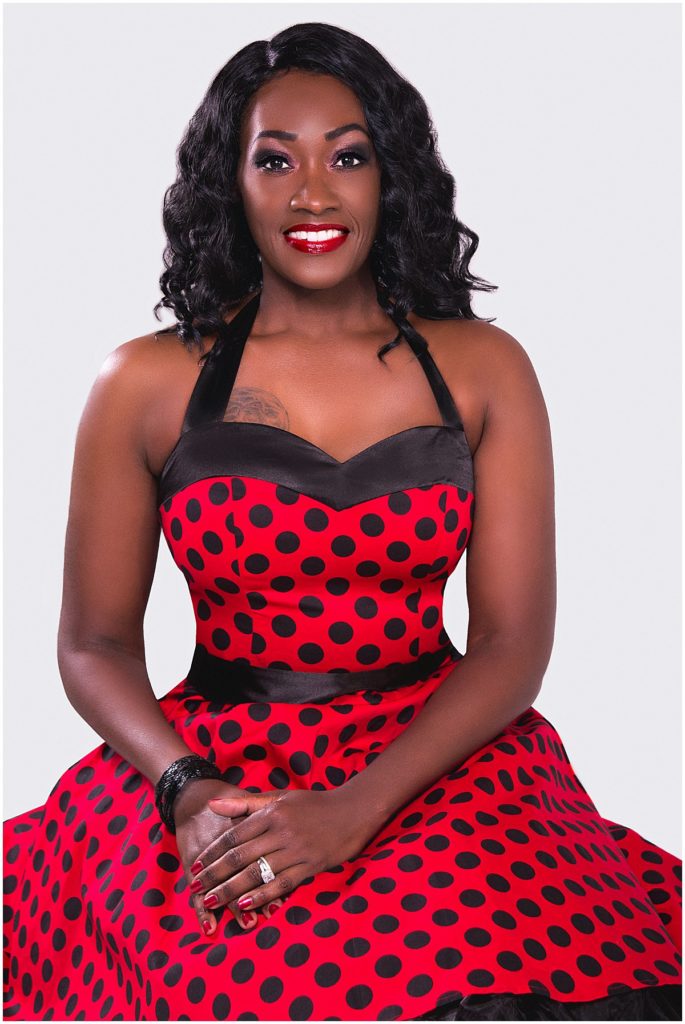 A black woman in a red and black polka dot dress poses for her birthday photo session