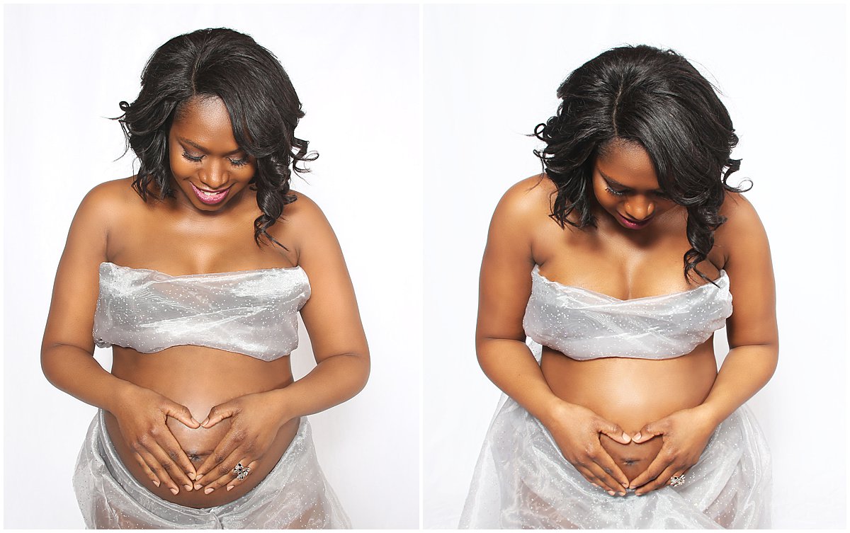 A black pregnant woman smiles at her belly during a Woodbridge maternity session