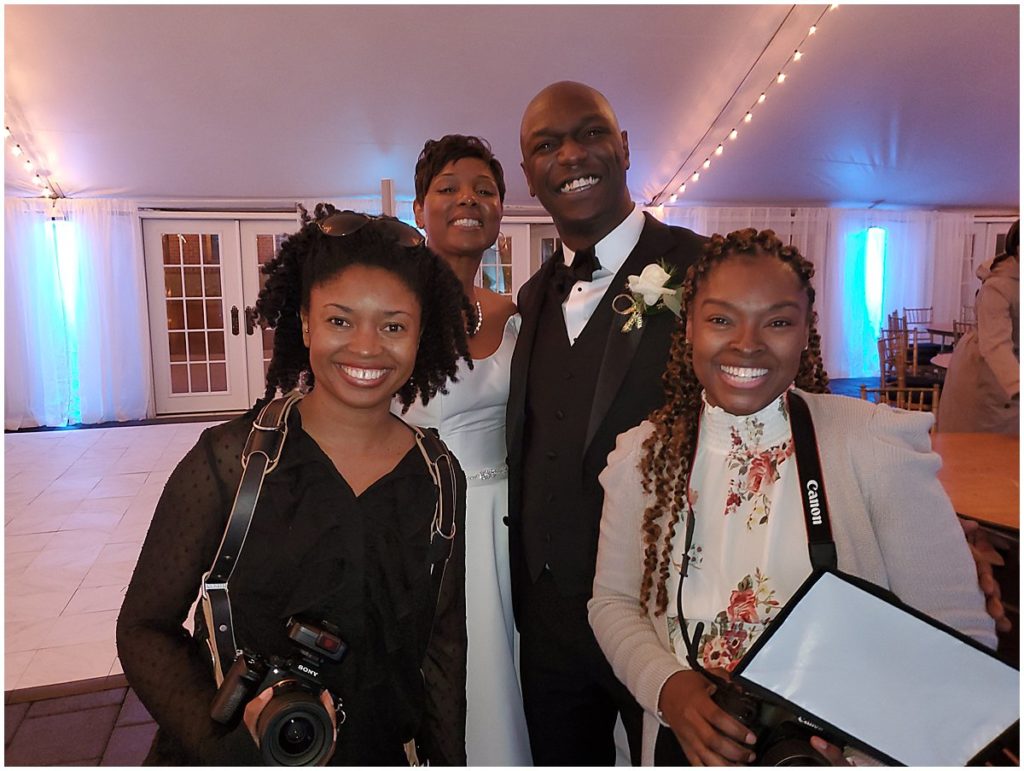 Two women carrying camera gear pose with a bride and groom in Richmond