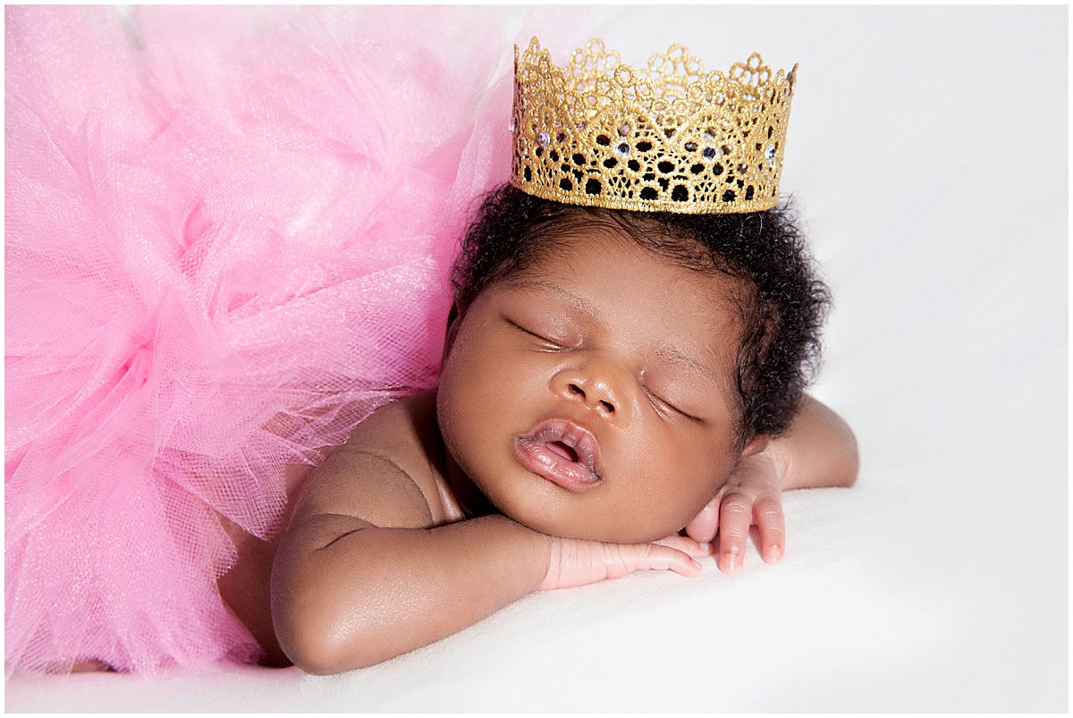 A baby girl dressed in a pink tutu sleeps during a newborn photography session