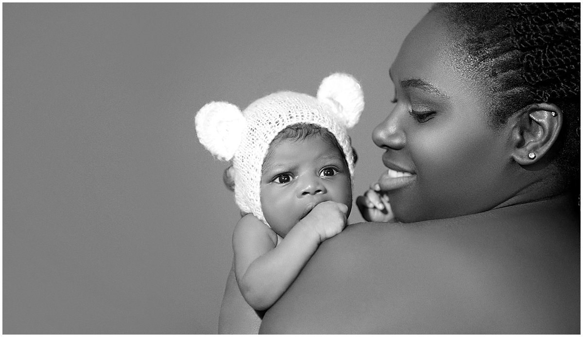 Mother holds baby over her shoulder during a newborn photography session