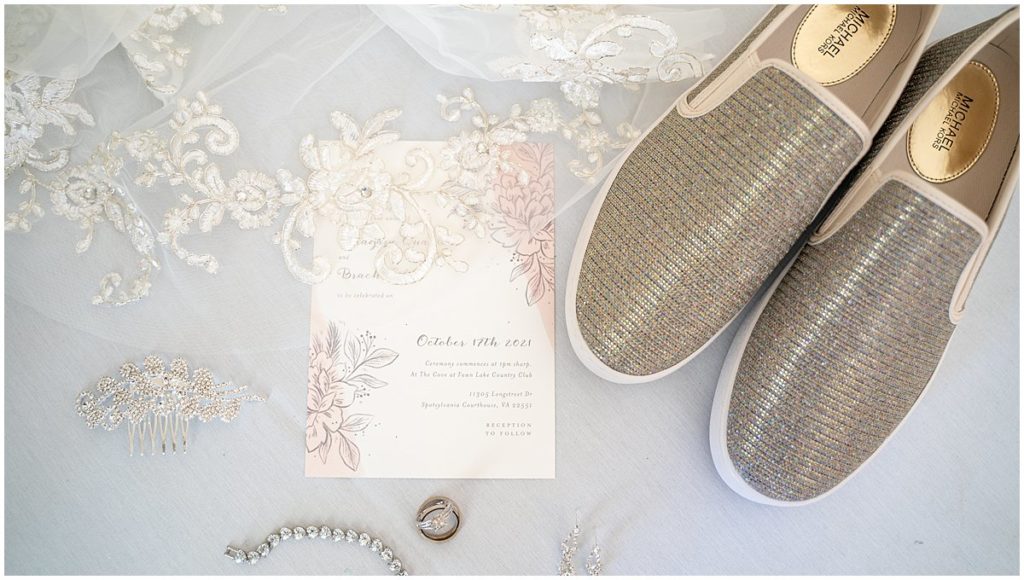 Wedding invitation is surrounded by bride's sneakers, rings and jewelry