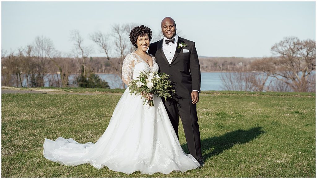 Couple dressed in wedding attire pose in front of the River Farm in Alexandria, Virginia.
