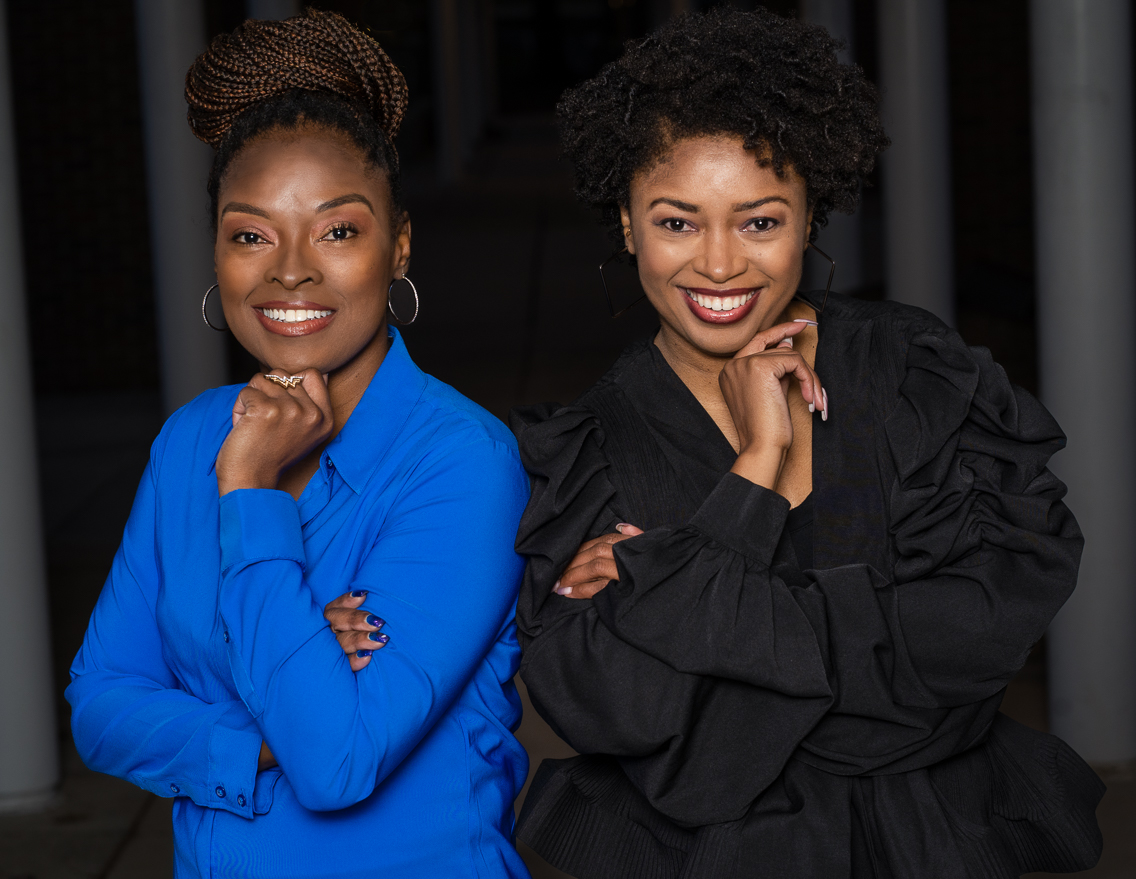 two African-American women pose together, one in blue and one in black.