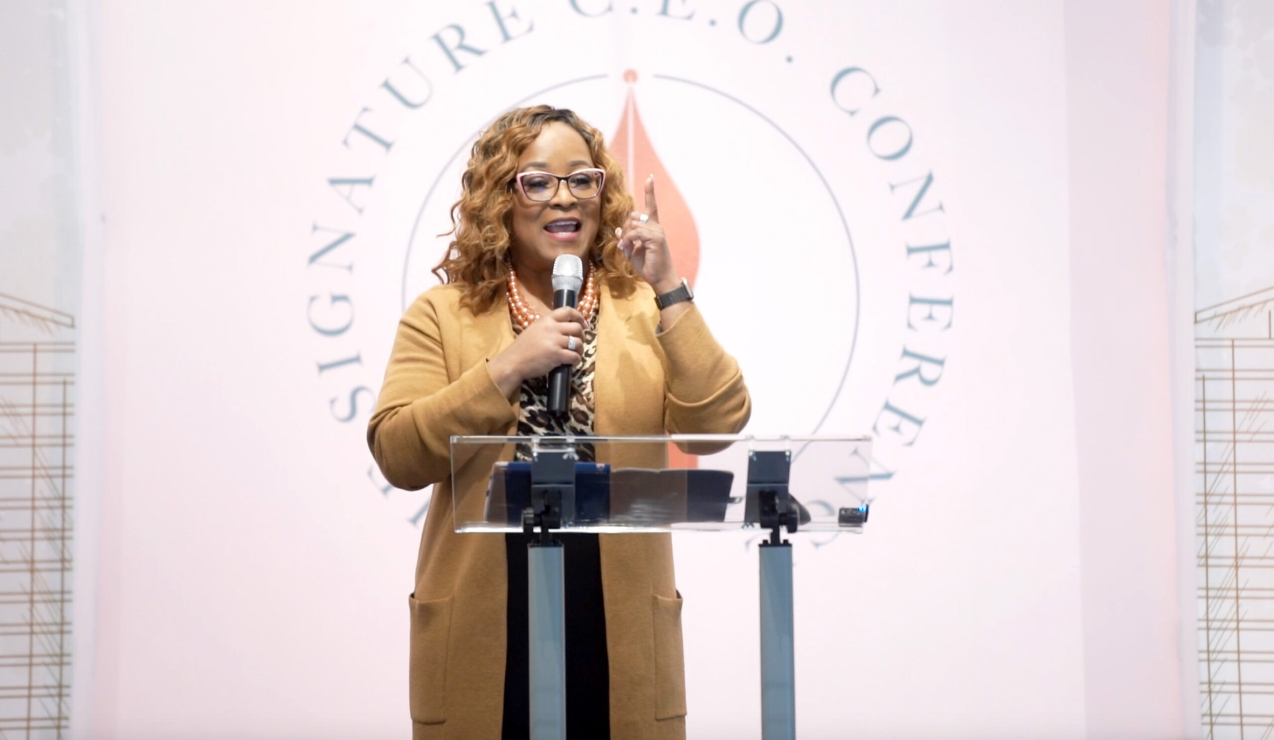 screenshot from video of a speaker in front of a backdrop that says Signature C.E.O. Conference.